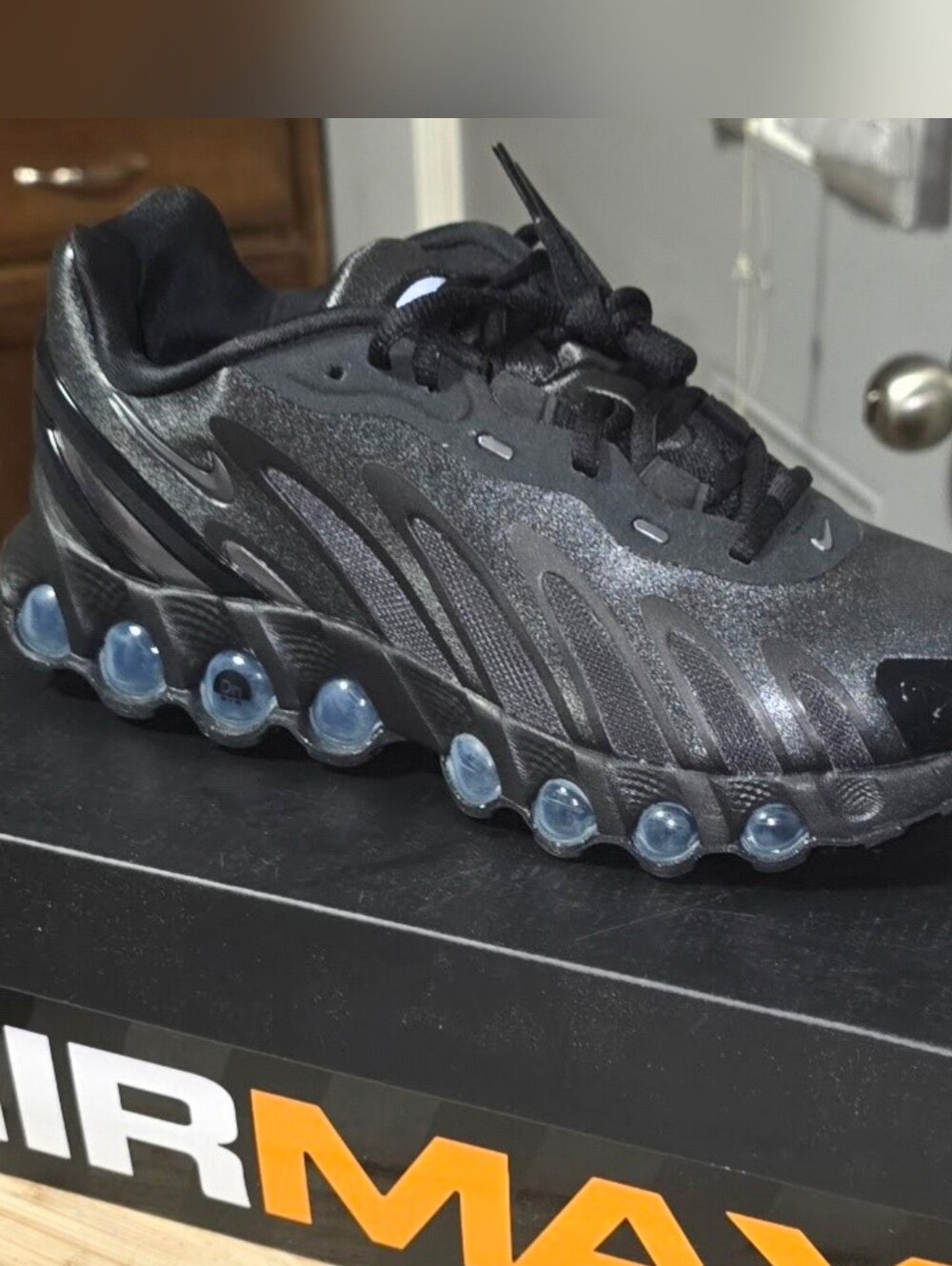 These are the Nike Air Max Dn8 shoes in a black and metallic dark grey colorway,